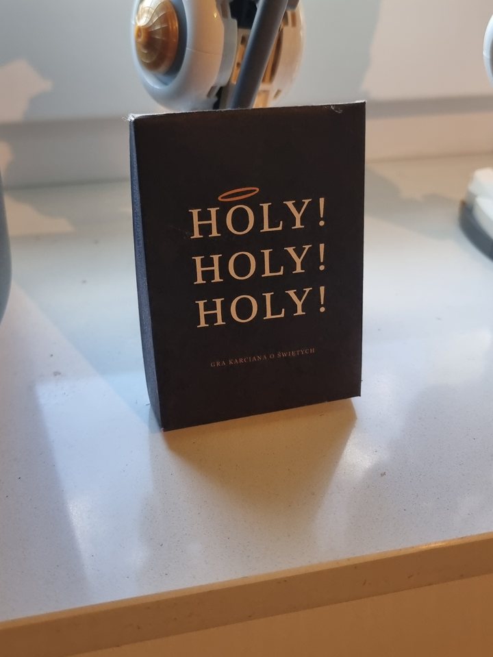 Czarne pudełko z napisem HOSANNA! stojące na parapecie, za nim robot z klocków